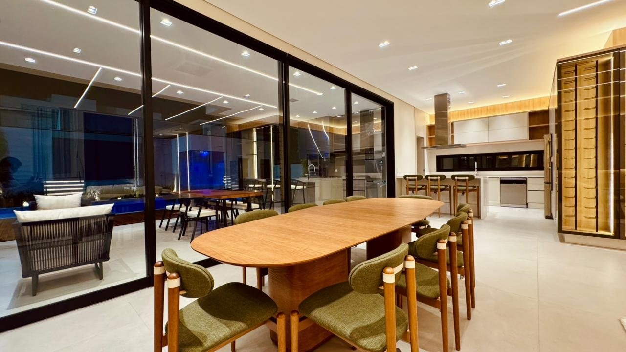 Sala de jantar com mesa de madeira e cadeiras verdes, integrada à área gourmet.
